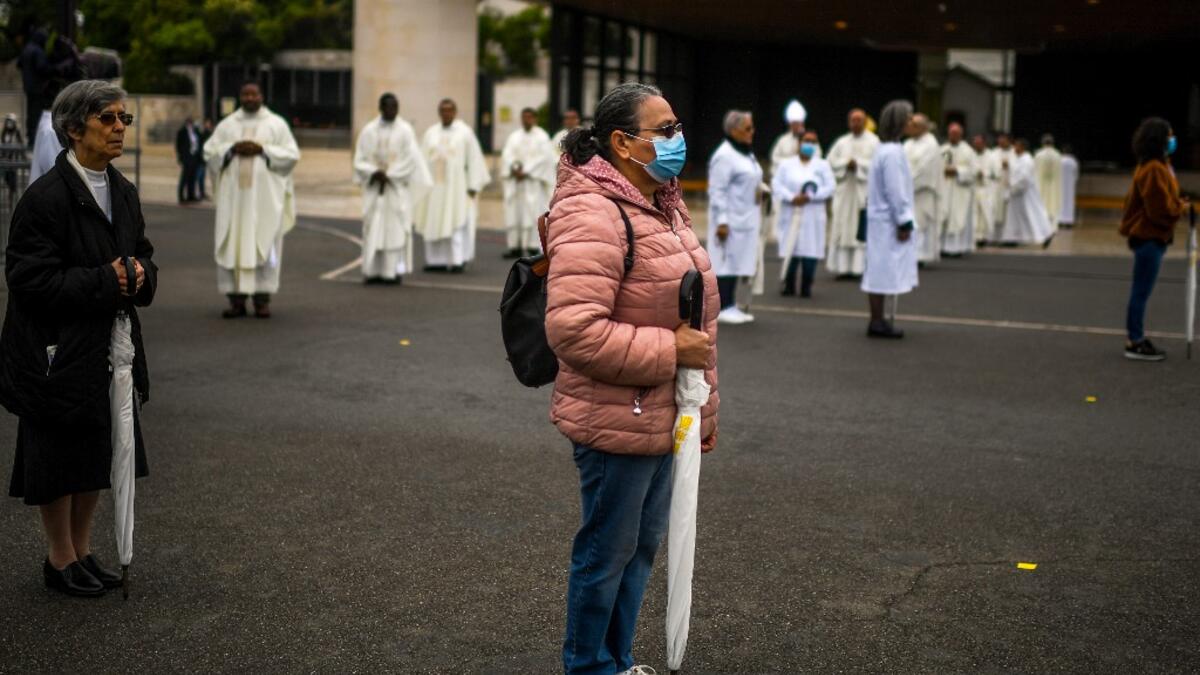 People attend a ceremony marking the 103rd anniversary of the apparitions of Our Lady of Fatima at the Fatima shrine in central Portugal, on May 13, 2020. Without the crowd of pilgrims it welcomes every year, the shrine of Fatima celebrated the anniversary during a religious ceremony reduced to the bare minimum. PATRICIA DE MELO MOREIRA / AFP
