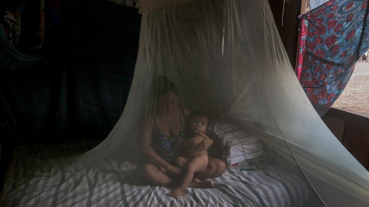 Satere-Mawe indigenous mother Priscila Tavares Batista, 36 remains in a bed protected by a mosquito net with her son Jone Tavares, 2, after being treated with medicinal herbs after showing symptoms of COVID-19, in the Wakiru community, in Taruma neighbourhood, a rural area west of Manaus, Amazonas State, Brazil, on May 17, 2020, during the novel coronavirus pandemic.Ricardo OLIVEIRA / AFP