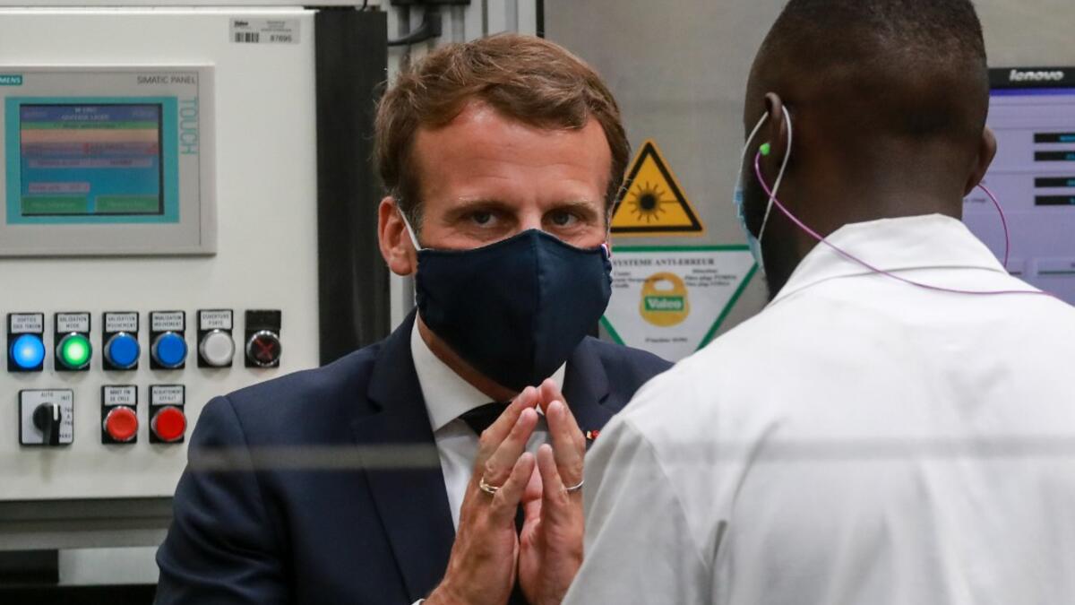 French President Emmanuel Macron, wearing a face mask, speaks to a worker as he visits the factory of manufacturer Valeo in Etaples, near Le Touquet, northern France on May 26, 2020 as part of the launch of a plan to rescue the French car industry. Ludovic MARIN / POOL / AFP