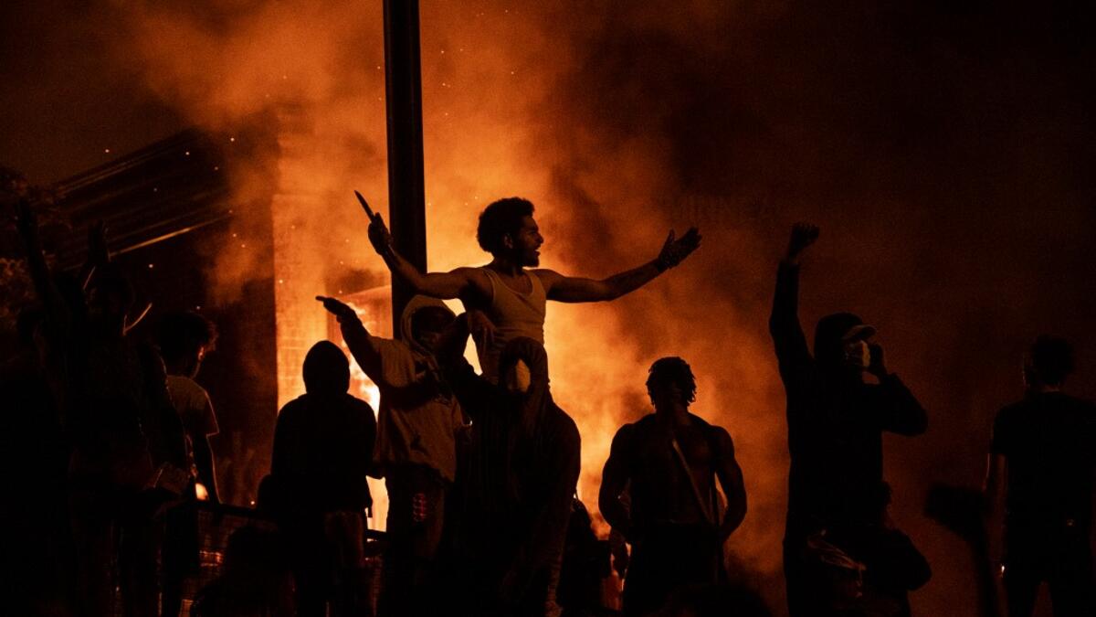 Protesters cheer as the Third Police Precinct burns behind them on May 28, 2020 in Minneapolis, Minnesota. As unrest continues after the death of George Floyd police abandoned the precinct building, allowing protesters to set fire to it. Stephen Maturen/Getty Images/AFP Stephen Maturen / GETTY IMAGES NORTH AMERICA / Getty Images via AFP