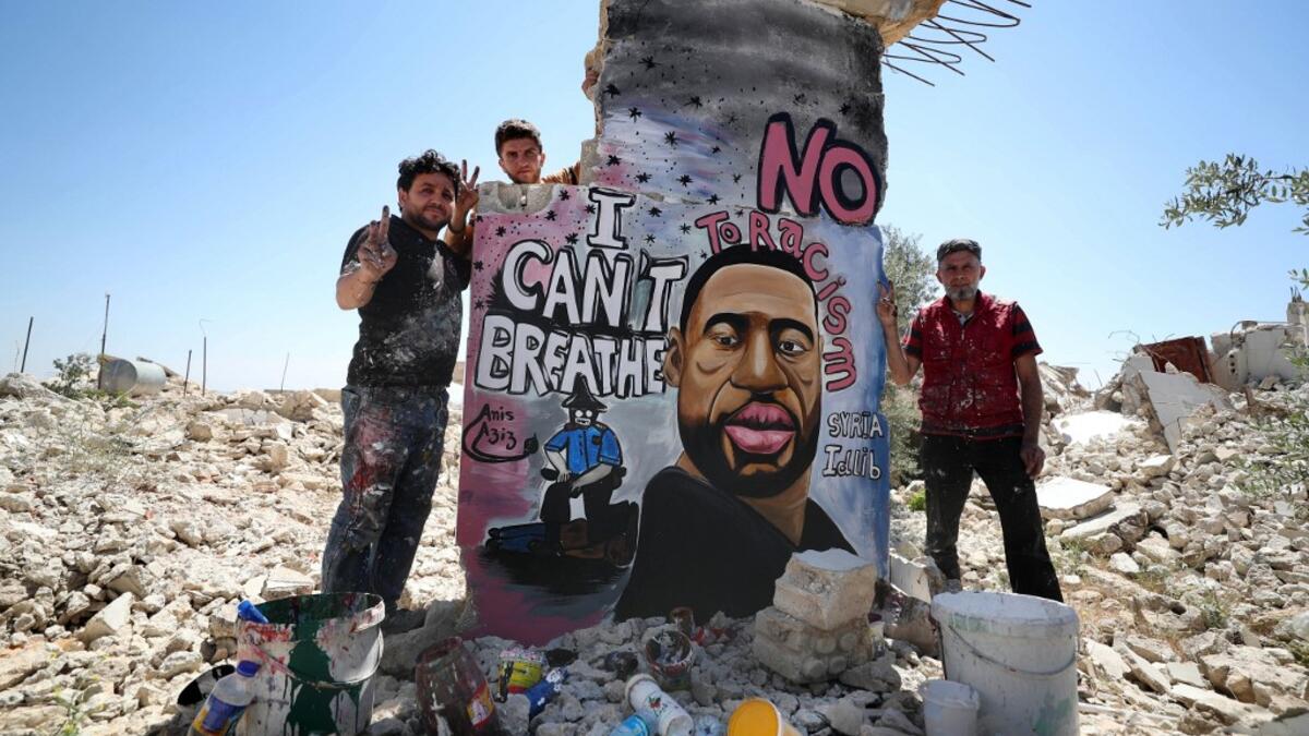 Syrian artists Aziz Asmar and Anis Hamdoun finish a mural depicting George Floyd, an unarmed African-American man who died while while being arrested and pinned to the ground by the knee of a Minneapolis police officer, in the town of Binnish in Syria's northwestern Idlib province on June 1, 2020. OMAR HAJ KADOUR / AFP