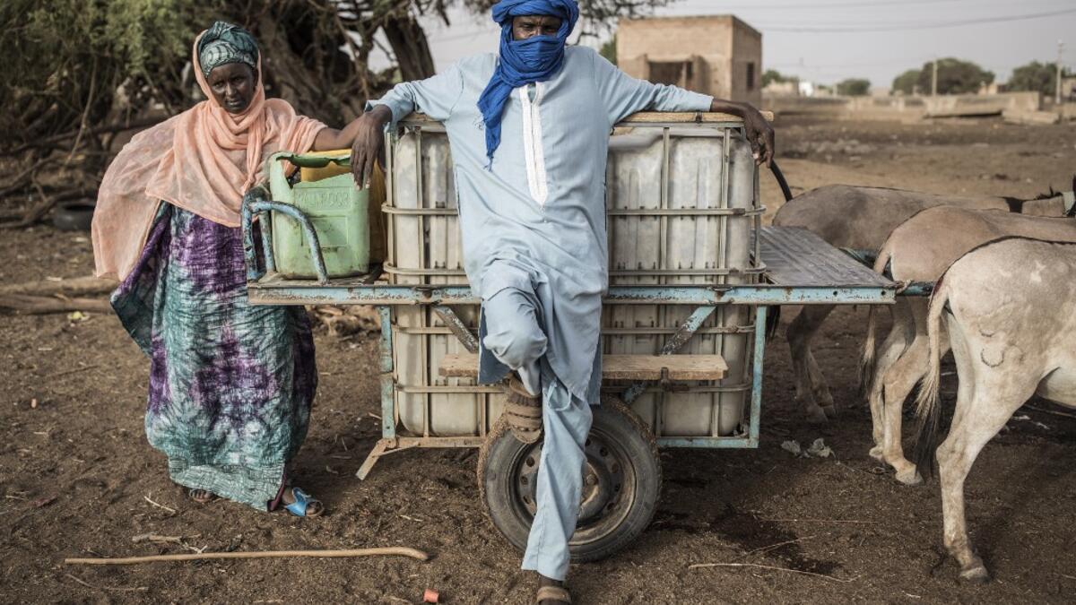 Fulani herders fill up their water tanks to take back to their camp at a unofficial herders market in Barkedji on May 28, 2020. Access to water comes at a price, many families must travel up to ten kilometres everyday to fill up their water supply, which then will be used for their livestock and themselves. COVID-19 coronavirus restrictions have closed down markets and regional movement, as a result Fulani herders are struggling to move to areas with more grazing land for there live stock. JOHN WESSELS / AF