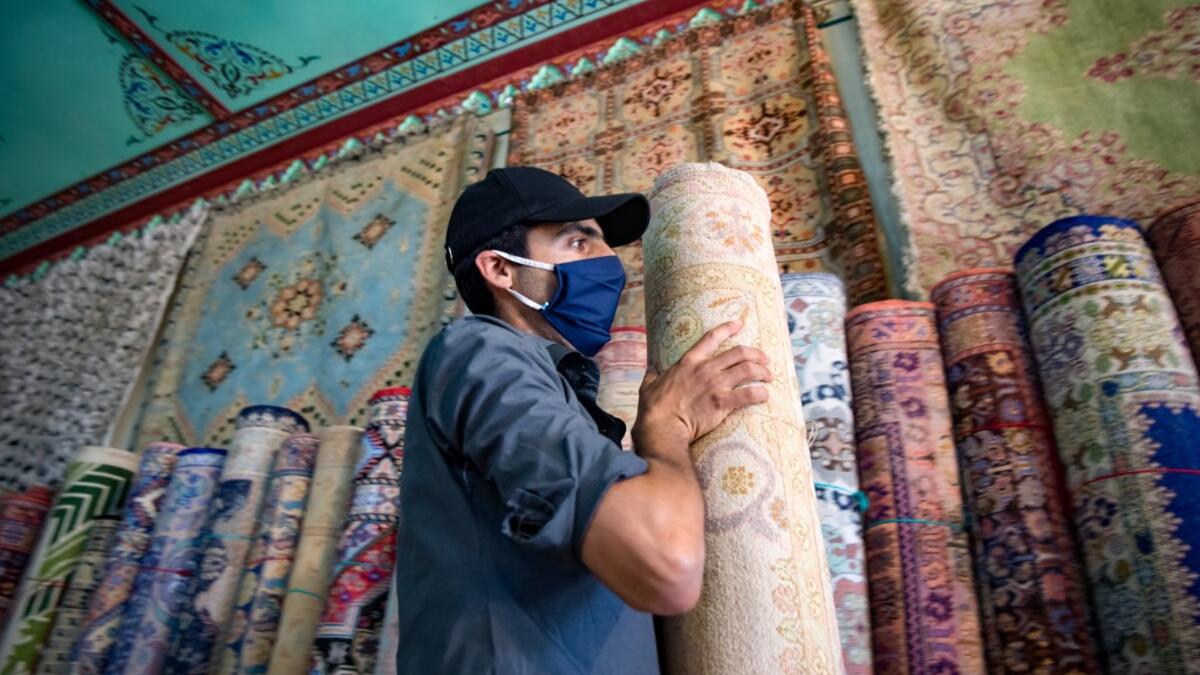 A Moroccan rug dealer lines up carpets at a shop in the city of Sale, north of the capital Rabat, on June 3, 2020, during the novel coronavirus pandemic. Artisans in Morocco have been starved of income for almost three months because of the COVID-19 pandemic. The crafts industry represents some seven percent of GDP, with an export turnover last year of nearly 1 billion dirhams ($100 million). FADEL SENNA / AFP
