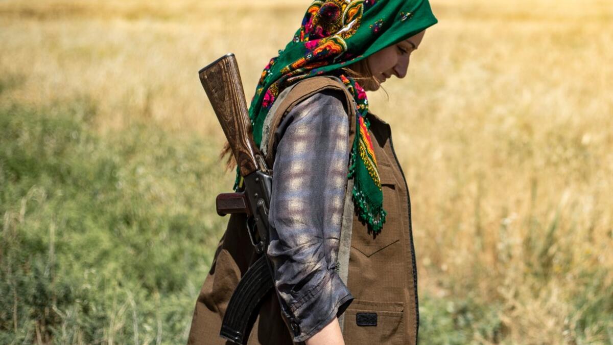 A Kurdish female volunteer, from the newly formed Community Protection Forces, guards a wheat field, against threats by jihadists to burn the crops, during harvest season on June 13, 2020, in the countryside east of Qamishli in Syria's northeastern Hasakah province. Delil SOULEIMAN / AFP