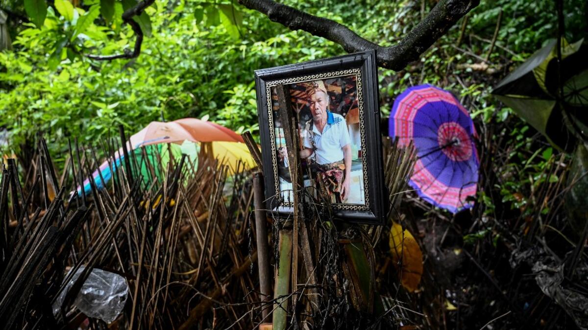 This picture taken on February 20, 2020 shows a photo of one of the deceased next to bamboo cages which cover bodies at a cemetery where Bali's Trunyanese people hold open-air burials - before restrictions were implemented due to the COVID-19 coronavirus - near the village of Trunyan in Bangli Regency, near Lake Batur on Bali island. SONNY TUMBELAKA / AFP