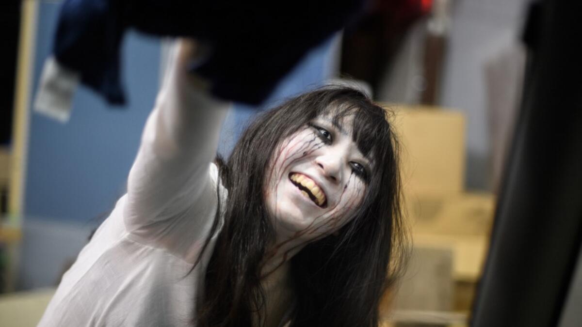 This picture taken on June 15, 2020 shows actress Haruna Suzuki, 20, cleaning up fake blood from the window of a car following a demonstration of a drive-in haunted house at a garage in Tokyo. A car horn beeps and the horror begins: a bloody murder and rampaging zombies. But this drive-in haunted house in Japan protects against the most terrifying enemy of all -- coronavirus. Inside a car, guests can scream as loudly as they like, with no mask required, as hideous creatures daubed in blood swarm towards the