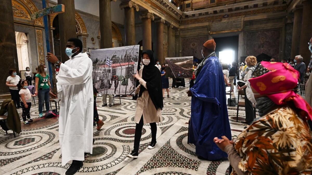 Priests and faithful, wearing protective face masks over their traditional dress and respecting security distances, attend a vigil prayer for the deceased would be migrants as part of the International Migrants Day, in Rome's Basilica of Our Lady in Trastevere neighbourhood on June 18, 2020. The Community of Sant'Egidio organised a prayer for all 2039 people died in the Mediterranean during the 2019, speaking if even their name is today unknown to men, they are in the heart of God. Vincenzo PINTO / AFP