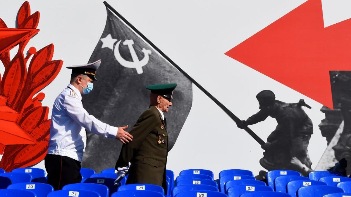 A police officer assists a veteran prior to a military parade, which marks the 75th anniversary of the Soviet victory over Nazi Germany in World War Two, at Dvortsovaya Square in Saint Petersburg on June 24, 2020. The parade, usually held on May 9, was postponed this year because of the coronavirus pandemic. OLGA MALTSEVA / AFP