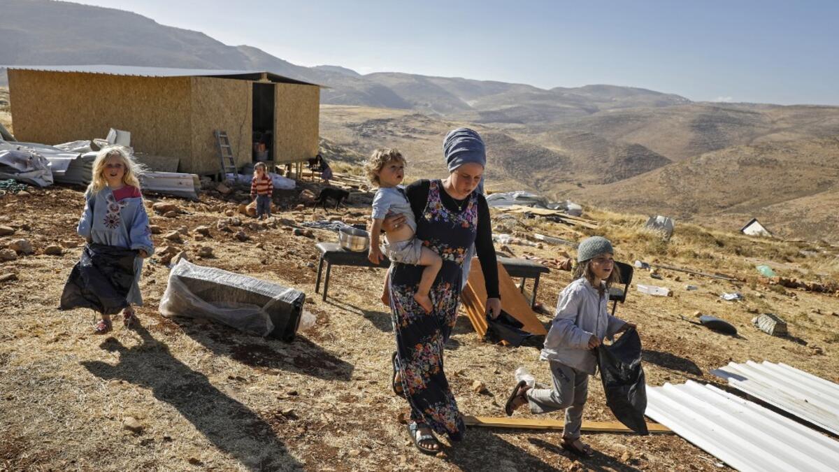 An Israeli settler woman walks with children in the Maoz Ester outpost located next to the Israeli settlement of Kokhav HaShahar in the occupied West Bank on June 18, 2020. The government of Israeli Prime Minister Benjamin Netanyahu has said it could begin the process to annex Jewish settlements in the West Bank as well as the strategic Jordan Valley from July 1. The plan -- endorsed by Washington -- would see the creation of a Palestinian state, but on reduced territory, and without Palestinians' core dema