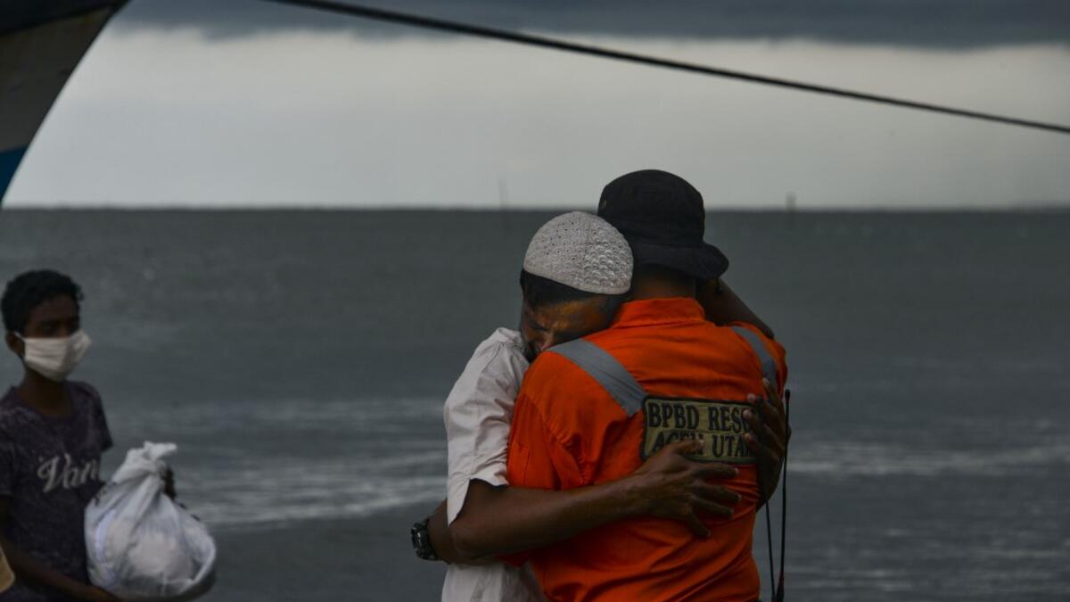 A Rohingya man from Myanmar hugs an Indonesian officer after being evacuated from a boat onto the shorelines of Lancok village, in Indonesia's North Aceh Regency on June 25, 2020. Nearly 100 Rohingya from Myanmar, including 30 children, have been rescued from a rickety wooden boat off the coast of Indonesia's Sumatra island, a maritime official said. CHAIDEER MAHYUDDIN / AFP