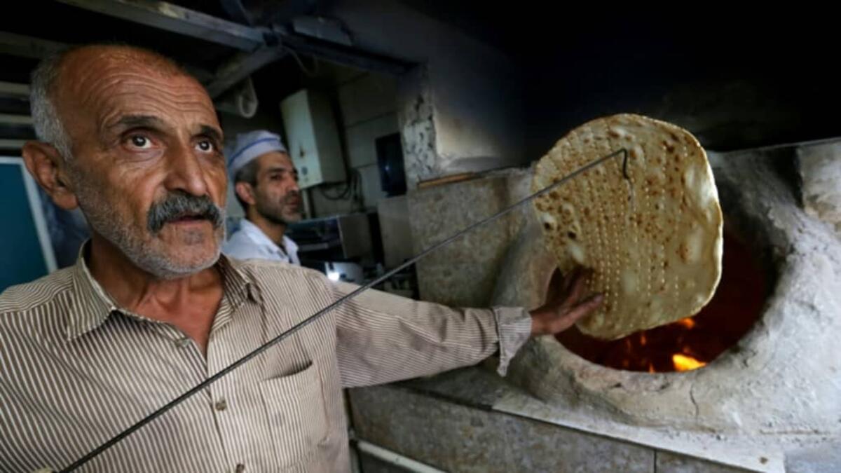 Iranian bakers Amir Jafari (L), 58, and Mohammad Mirzakhani, 41, make Taftoon bread in Tehran on June 13, 2020. ATTA KENARE / AFP
