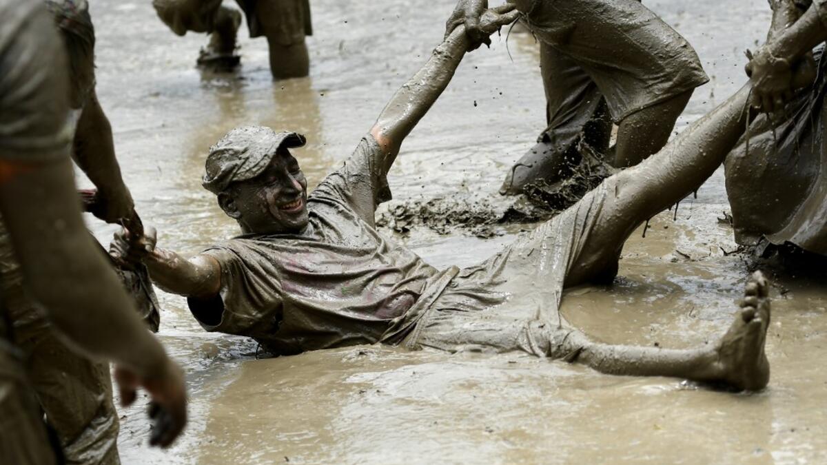 Mud-covered farmers play in a rice paddy field during "National Paddy Day", which marks the start of the annual rice planting season, in Tokha village on the outskirts of Kathmandu on June 29, 2020. Splashing mud and drinking local rice beer, Nepali farmers this week celebrated National Paddy Day to mark the beginning of the rice-planting season, despite some coronavirus lockdown measures still in place. Traditional farming songs and laughter echoed in the air as farmers waded into waterlogged fields to sow