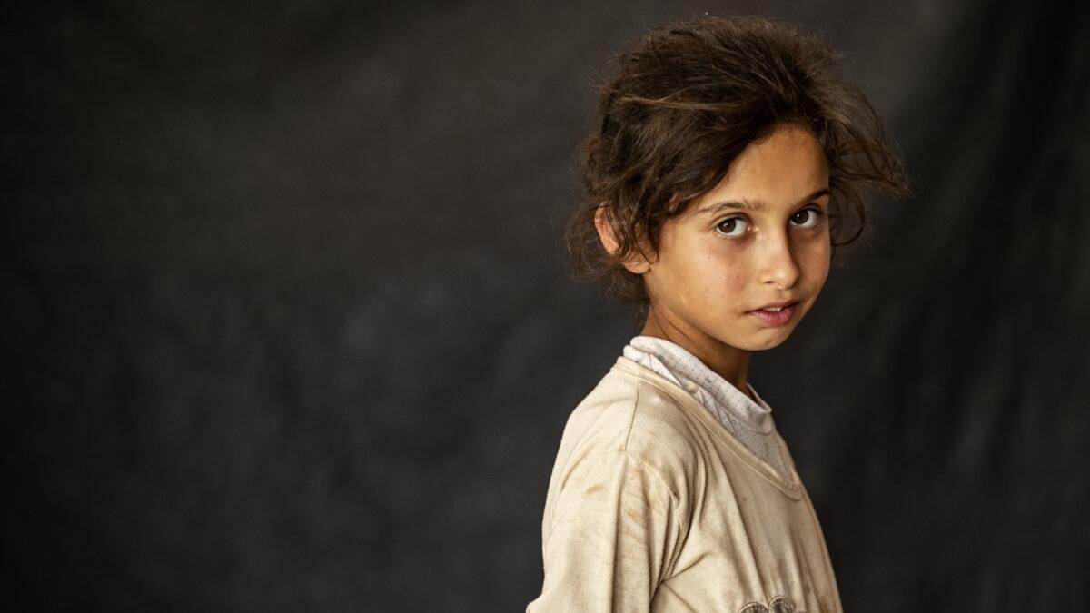 A girl poses for a picture while at a school building where Syrians -- displaced from the area of Ras al-Ain by the Turkish offensive on the northeast -- are staying in the city of Hasakah, on June 30, 2020. Delil SOULEIMAN / AFP