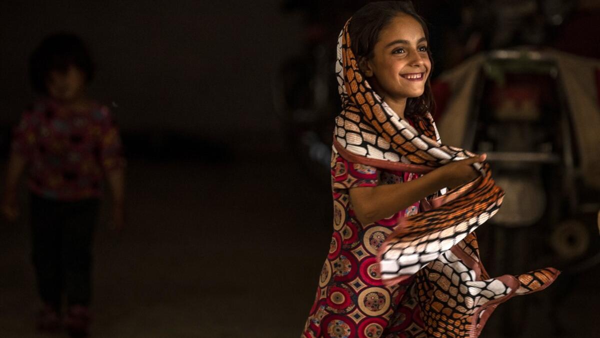 A girl holds her shawl while walking in a hallway at a school building where Syrians -- displaced from the area of Ras al-Ain by the Turkish offensive on the northeast -- are staying in the city of Hasakah, on June 30, 2020. Delil SOULEIMAN / AFP