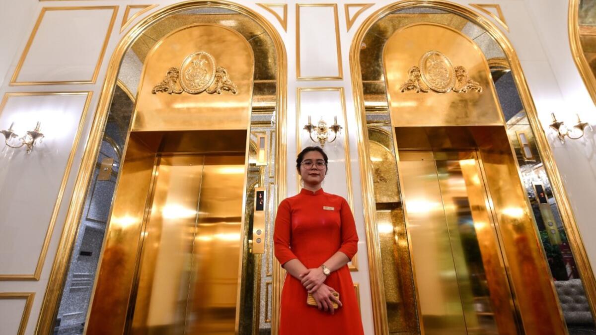 A staff member stands near the lifts in the lobby of the newly-inaugurated Dolce Hanoi Golden Lake hotel, the world's first gold-plated hotel, in Hanoi on July 2, 2020. Manan VATSYAYANA / AFP