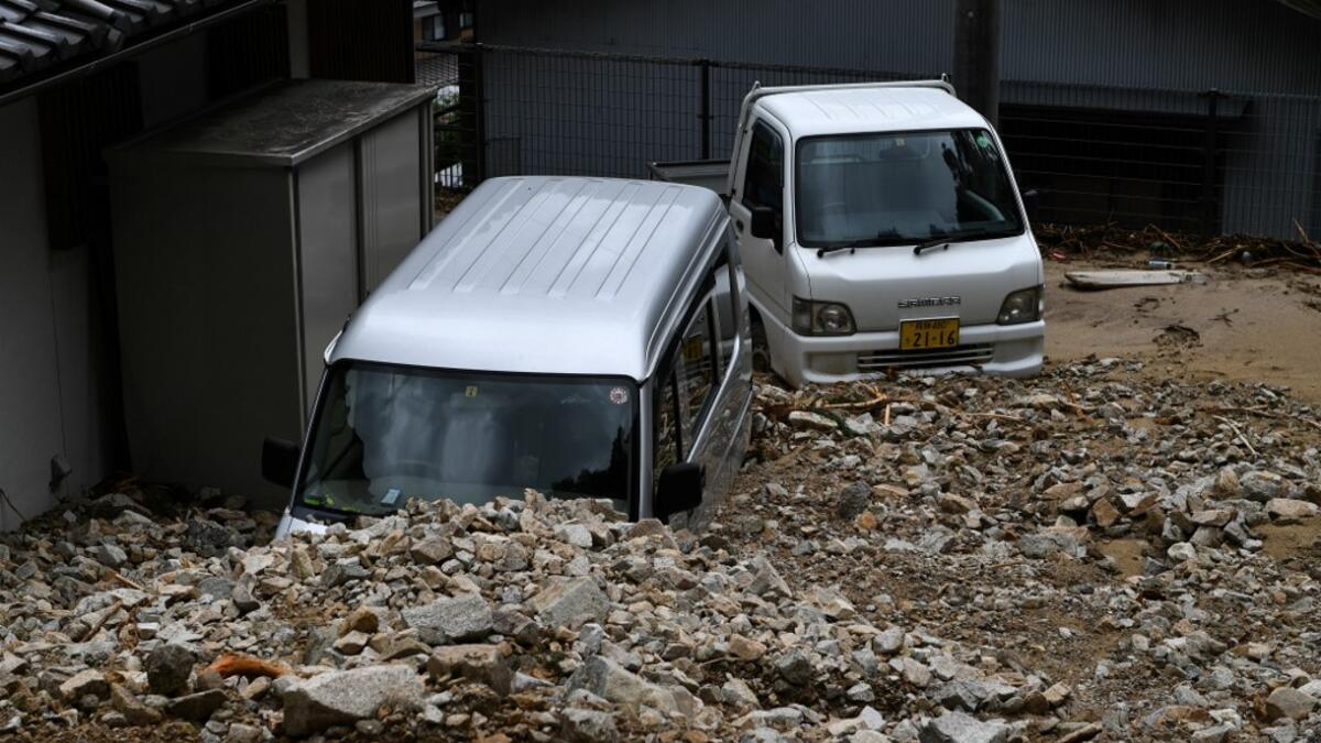 Damaged vehicles are seen under rocks from a mudslide following heavy rains and flooding in the village of Gero, Gifu prefecture on July 9, 2020. Japanese emergency services and troops were scrambling to reach thousands of homes cut off by devastating flooding and landslides that have killed dozens and caused widespread damage. Philip FONG / AFP