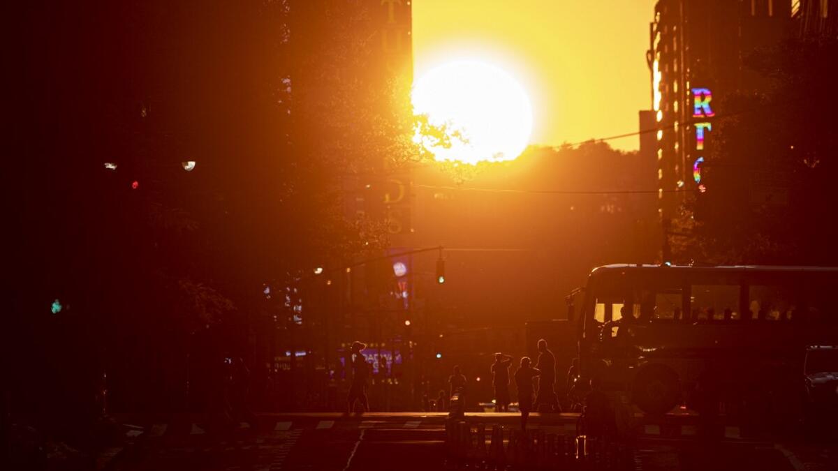 The sun sets along 42nd Street, during the so called "Manhattanhenge", on July 13, 2020 in New York City. The so called Manhattanhenge happens four times each year, when when the sun rises or sets in New York City parallel to the city street grid in Manhattan. Johannes EISELE / AFP