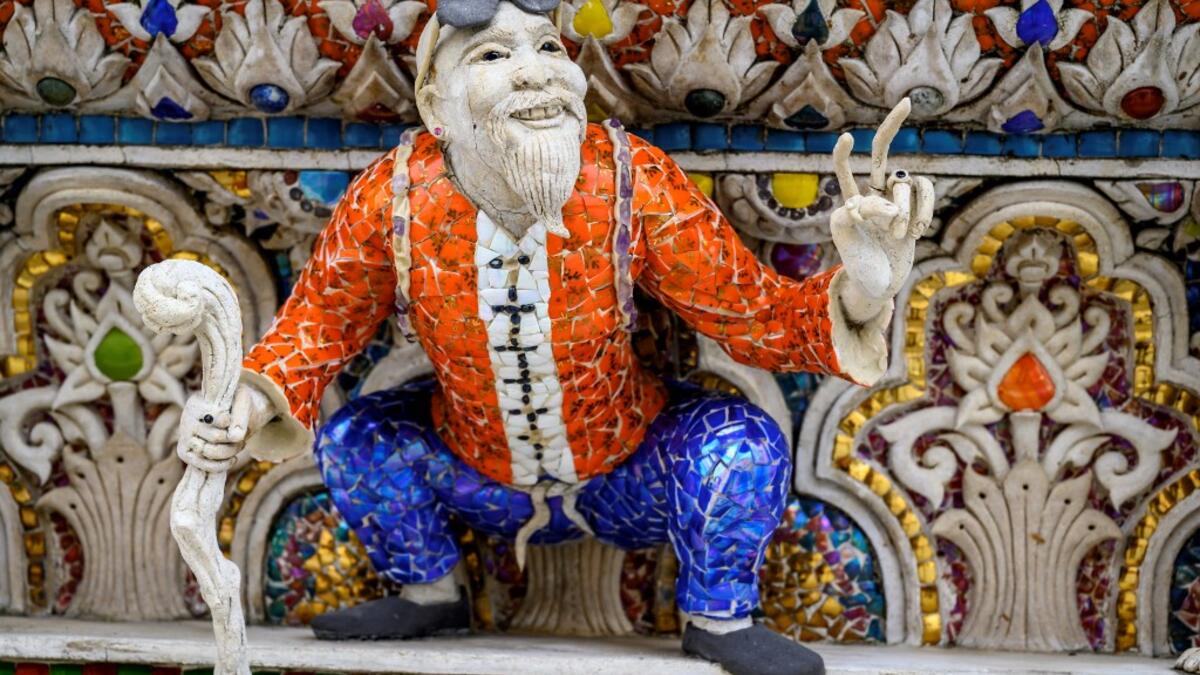 This photograph taken on July 14, 2020 shows the Dragon Ball manga character Master Roshi on the facade of the Wat Pariwat Buddhist temple in Bangkok. Wat Pariwat, also known as "the David Beckham Temple", is decorated with statues of superheroes and comic characters as well as mythical and imaginary creatures. A golden-plated sculpture of the English football player holding the base of a Buddha statue in one of the buildings gives the temple its nickname. Mladen ANTONOV / AFP