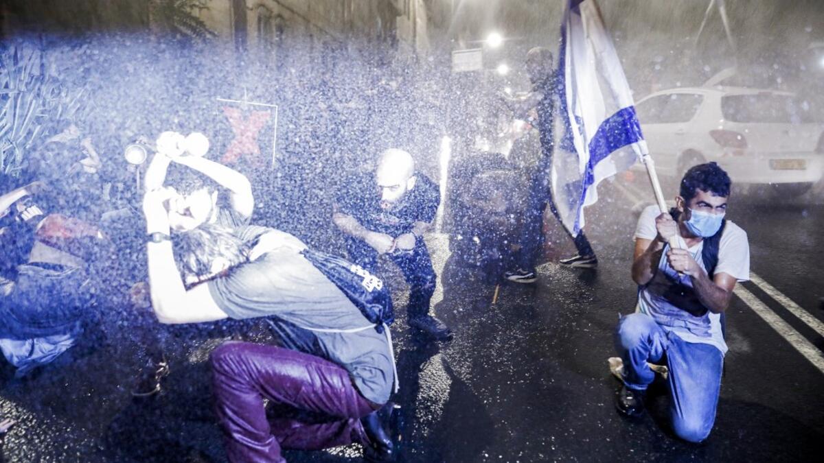 Israeli police spray protesters (clad in masks due to the COVID-19 coronavirus pandemic) with water cannon during an anti-government demonstration in Jerusalem, on July 18, 2020. Ahmad GHARABLI / AFP
