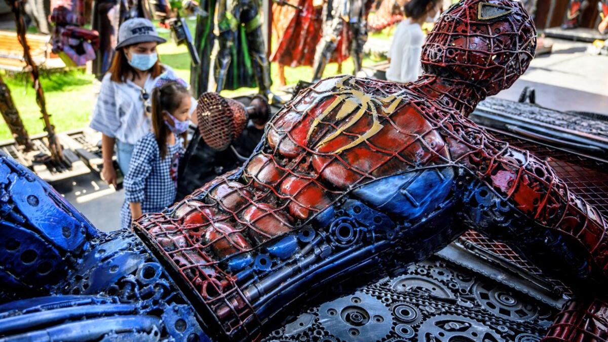 This photograph taken on July 18, 2020 shows tourists looking at a life-sized Spiderman sculpture made of scrap metal parts at the Ban Hun Lek museum in Ang Thong, some 100km north of Bangkok. "Ban Hun Lek" or "The House of Steel Robots" is a museum where a collective of artists display their scrap metal creations depicting popular comics and sci-fi film characters. Mladen ANTONOV / AFP