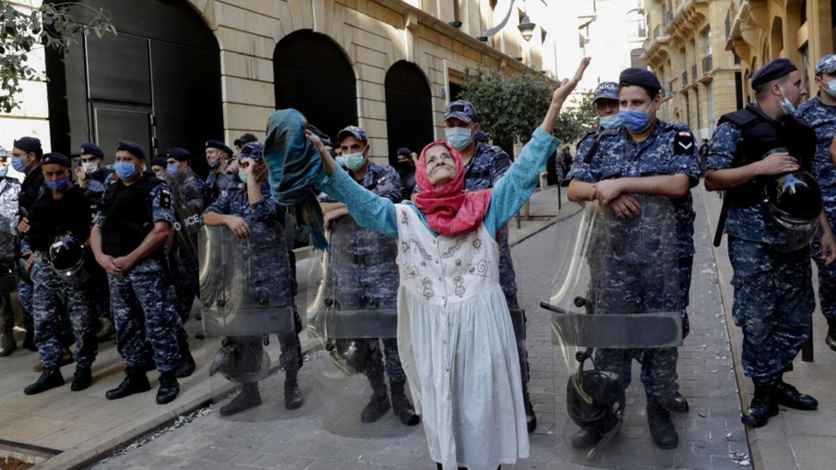 An elderly woman raises her arms in front of Lebanese security forces standing guard in front of the World Bank offices in the downtown district of the Lebanese capital Beirut on July 25, 2020, as demonstrators rally against the Bisri dam project, partly financed by the World Bank. The government says the Bisri dam is vital to tackling chronic water shortages. But activists say it will ravage most of the region's farmland and historic sites, and they also fear the consequences of building it on a seismic fa