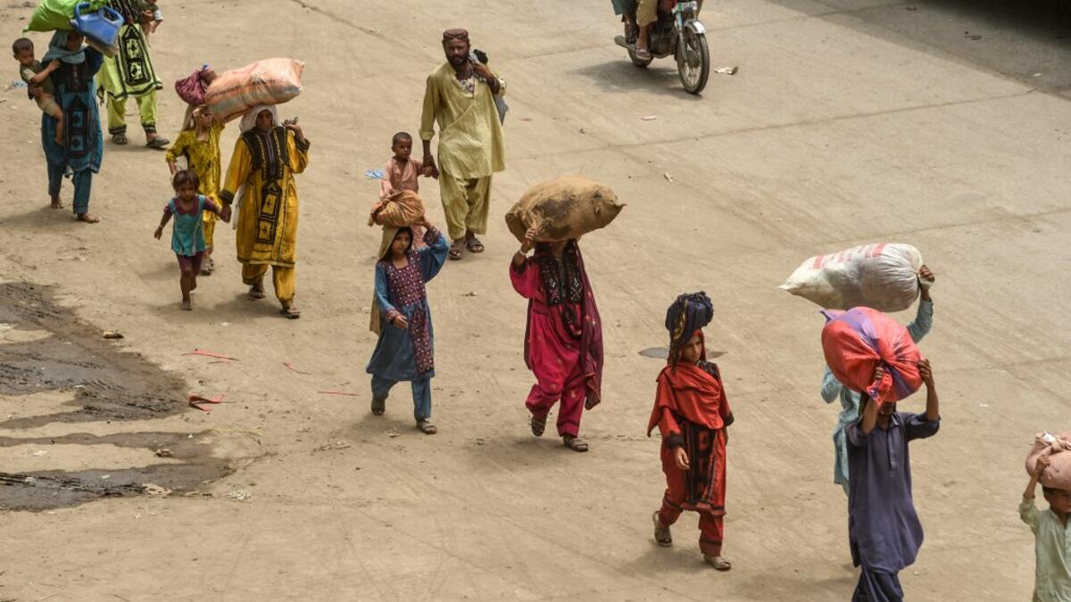 People carrying their belongings arrive at a bus station to go back home ahead of the Muslim festival Eid al-Adha or the 'Festival of Sacrifice' at a bus station in Lahore on July 30, 2020.  Arif ALI / AFP