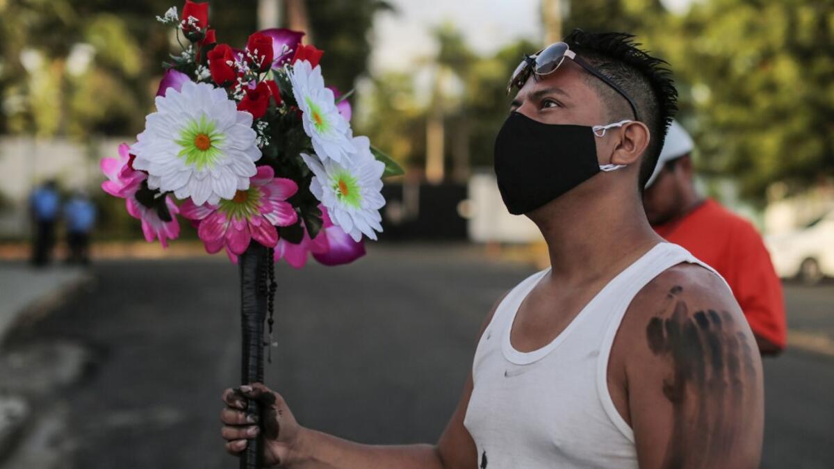 A Catholic faithful wears a face mask as a preventive measure against the spread of the novel coronavirus, COVID-19, during the opening of the ten-day celebration of the Santo Domingo de Guzman festival, outside the Las Sierritas de Santo Domingo church in Managua, on August 1, 2020. Despite the Catholic Church cancelling all religious activities due to the coronavirus pandemic, devotees gathered outside the church for the celebration.