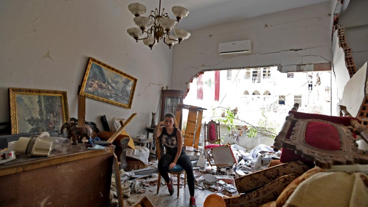 A woman sits amidst the rubble in her damaged house in the Lebanese capital Beirut on August 6, 2020, two days after a massive explosion shook the Lebanese capital. The blast, which appeared to have been caused by a fire igniting 2,750 tonnes of ammonium nitrate left unsecured in a warehouse, was felt as far away as Cyprus, some 150 miles (240 kilometres) to the northwest. The scale of the destruction was such that the Lebanese capital resembled the scene of an earthquake, with thousands of people left home
