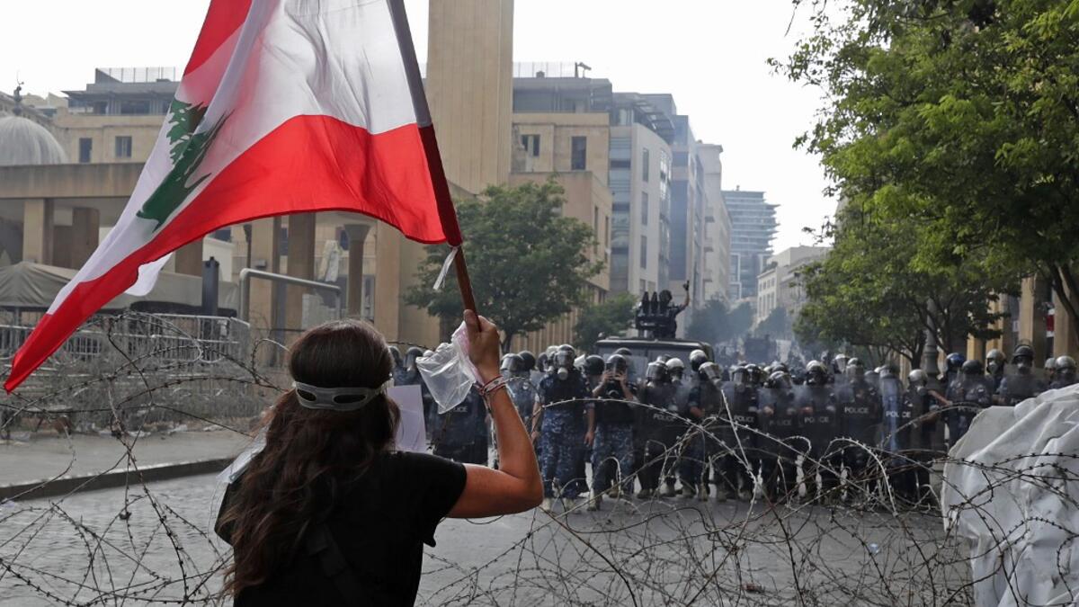 A Lebanese protester waves the national flag during clashes in downtown Beirut on August 8, 2020, following a demonstration against a political leadership they blame for a monster explosion that killed more than 150 people and disfigured the capital Beirut. ANWAR AMRO / AFP