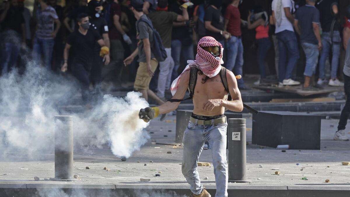 A Lebanese protester throws a tear-gas canister back at security forces in downtown Beirut on August 8, 2020, following a demonstration against a political leadership they blame for a monster explosion that killed more than 150 people and disfigured the capital Beirut. JOSEPH EID / AFP