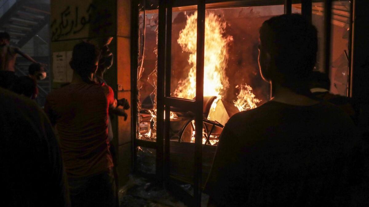 Lebanese protesters watch the flames inside the headquarters of the Lebanese association of banks in downtown Beirut on August 8, 2020, following a demonstration against a political leadership they blame for a monster explosion that killed more than 150 people and disfigured the capital Beirut. ANWAR AMRO / AFP