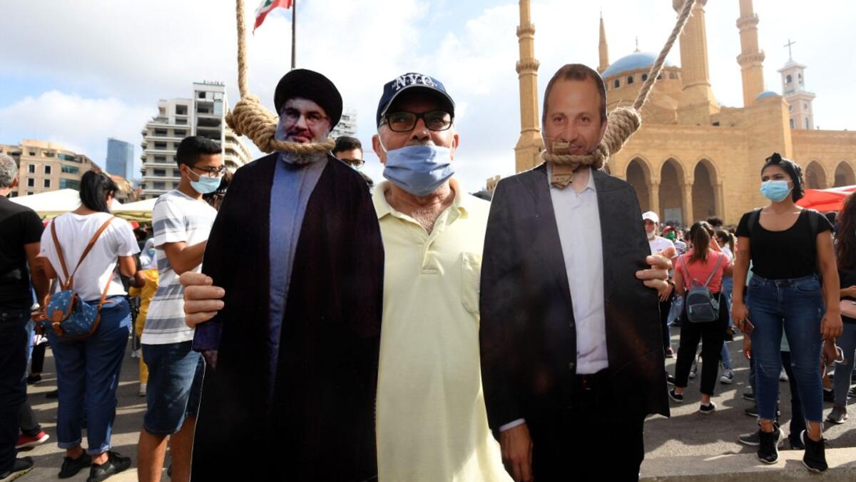 A man poses for a picture with a cardboard cut-out of Hassan Nasrallah (L), the head of Lebanon's Shiite Muslim movement Hezbollah, and former Foreign Minister Gibran Bassil hung by Lebanese protesters in downtown Beirut on August 8, 2020, during a demonstration against a political leadership they blame for a monster explosion that killed more than 150 people and disfigured the capital Beirut. AFP