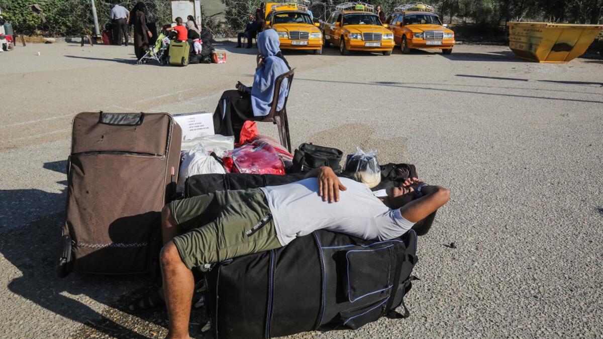 Palestinians rest as they wait to cross to the Egyptian side of Rafah border crossing after months of closure due to the coronavirus pandemic in the southern Gaza Strip, on August 11, 2020 . SAID KHATIB / AFP