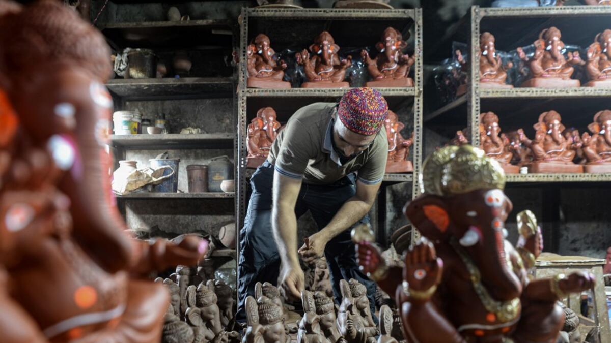 In this picture taken on August 11, 2020, Muslim potter Yusuf Zakaria Galwani inspects a clay idol of elephant headed Hindu god Ganesha at his workshop at Kumbharwada inside the Dharavi slums in Mumbai. After the coronavirus pandemic clobbered his pottery business, a Muslim artisan from India's largest slum turned to a Hindu god to revive his fortunes by making environmentally-friendly Ganesha idols for an upcoming festival. In Mumbai's Dharavi slum, Galwani worked alongside his two brothers to create 13-in