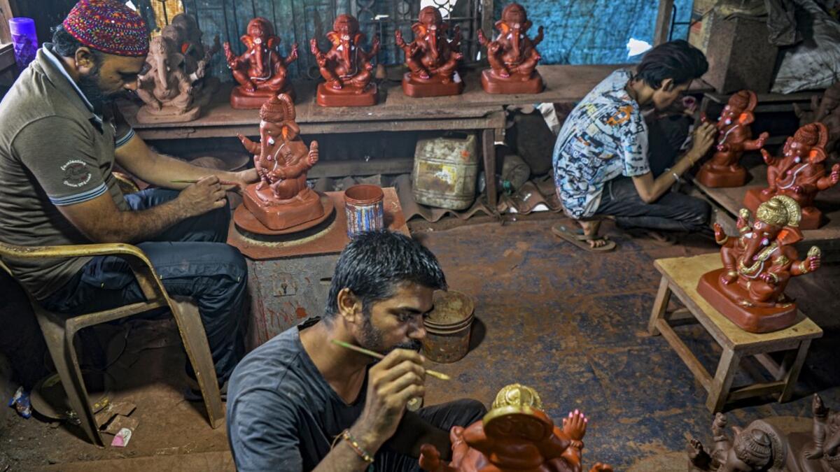 In this picture taken on August 15, 2020, Muslim potter Yusuf Zakaria Galwani (L) along with his staff, work on the idols of elephant headed Hindu god Ganesha at his workshop at Kumbharwada inside the Dharavi slums in Mumbai. After the coronavirus pandemic clobbered his pottery business, a Muslim artisan from India's largest slum turned to a Hindu god to revive his fortunes by making environmentally-friendly Ganesha idols for an upcoming festival. In Mumbai's Dharavi slum, Galwani worked alongside his two b