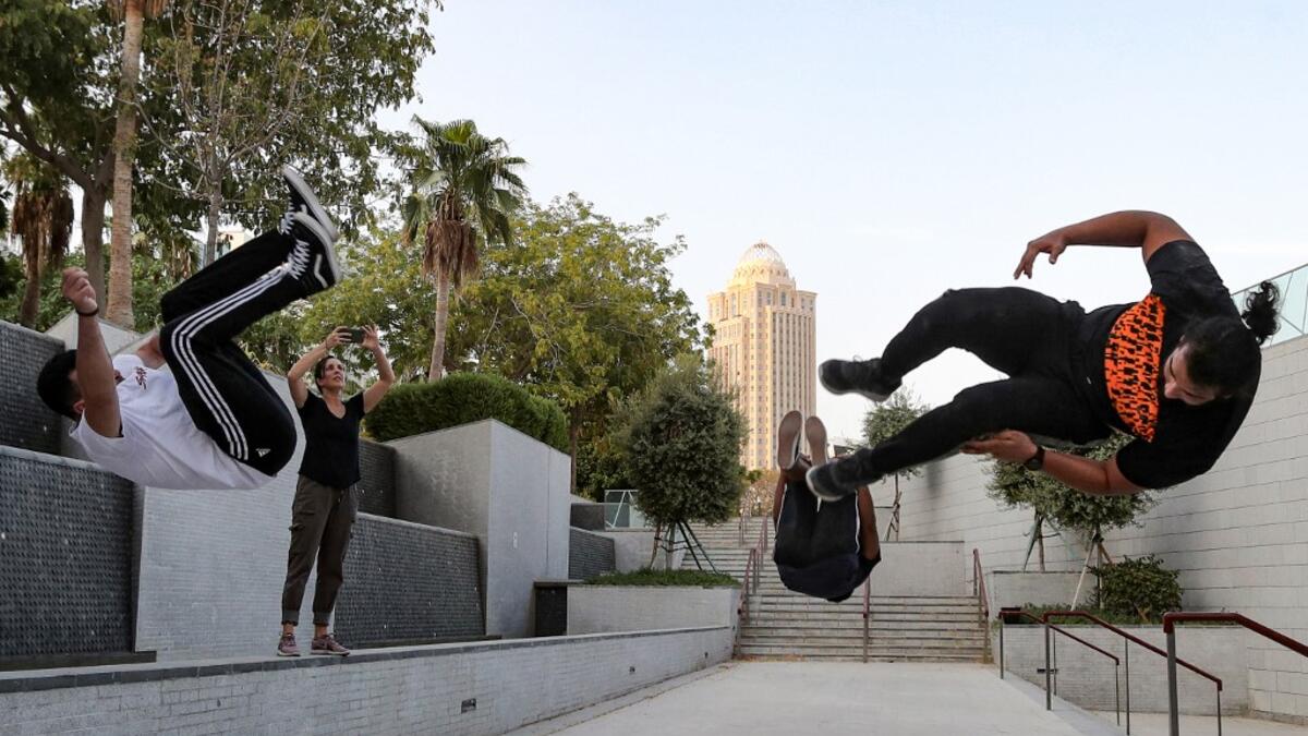 Hamzar Mekkaoui (R) , Achref Bejaoui (L) and a friend perform parkour, a sport that originated in France in the 1990s, which involves getting around urban obstacles with a fast-paced mix of jumping, vaulting, running and rolling, in the Qatari capital Doha, on August 11, 2020. Parkour, also known as free-running, has now found a small but committed following in Qatar despite evening temperatures that hover around 40 degrees Celsius (104 Fahrenheit) in summer and over-zealous security guards unfamiliar with