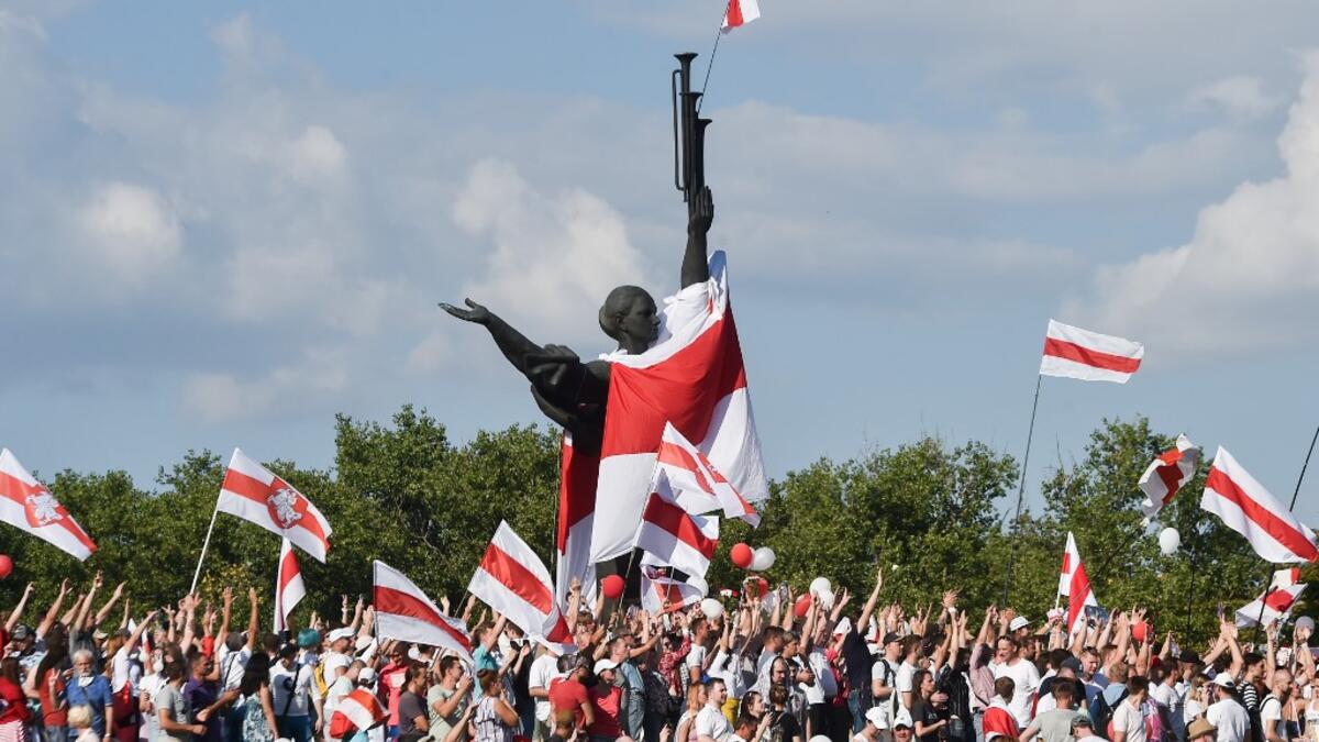 Belarus opposition supporters hold former white-red-white flags of Belarus used in opposition to the government, during a demonstration in central Minsk on August 16, 2020. The Belarusian strongman, who has ruled his ex-Soviet country with an iron grip since 1994, is under increasing pressure from the streets and abroad over his claim to have won re-election on August 9, with 80 percent of the vote. Sergei GAPON / AFP