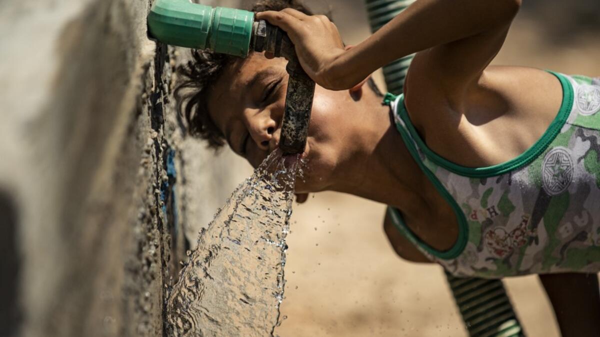 A Syrian boy drinks from the faucet of a water cistern provided by humanitarian organisations during a water outage in Syria's northeastern city of Hasakah on August 22, 2020. As coronavirus spreads across northeast Syria, residents in Hasakeh have been caught up in the latest spat between Turkish forces to the north and Syrian Kurds it views as "terrorists". In October last year, Turkish forces occupied a 120-stretch (70-mile) stretch of land inside the Syrian border, including the Alouk power station that