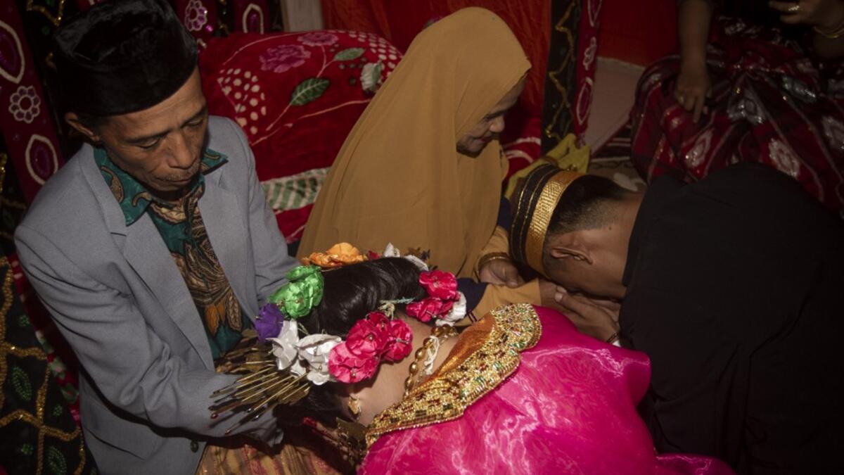 This picture taken on July 25, 2020 shows 18-year-old Lia (C) and her 21-year-old husband Randi (R, not their real names) asking for their parents' blessing after getting married in the village of Tampapadang in Mamuju, West Sulawesi. Child marriage has long been common in traditional communities from the Indonesian archipelago to India, Pakistan and Vietnam, but numbers had been decreasing as charities made inroads by encouraging access to education and women's health services. YUSUF WAHIL / AFP