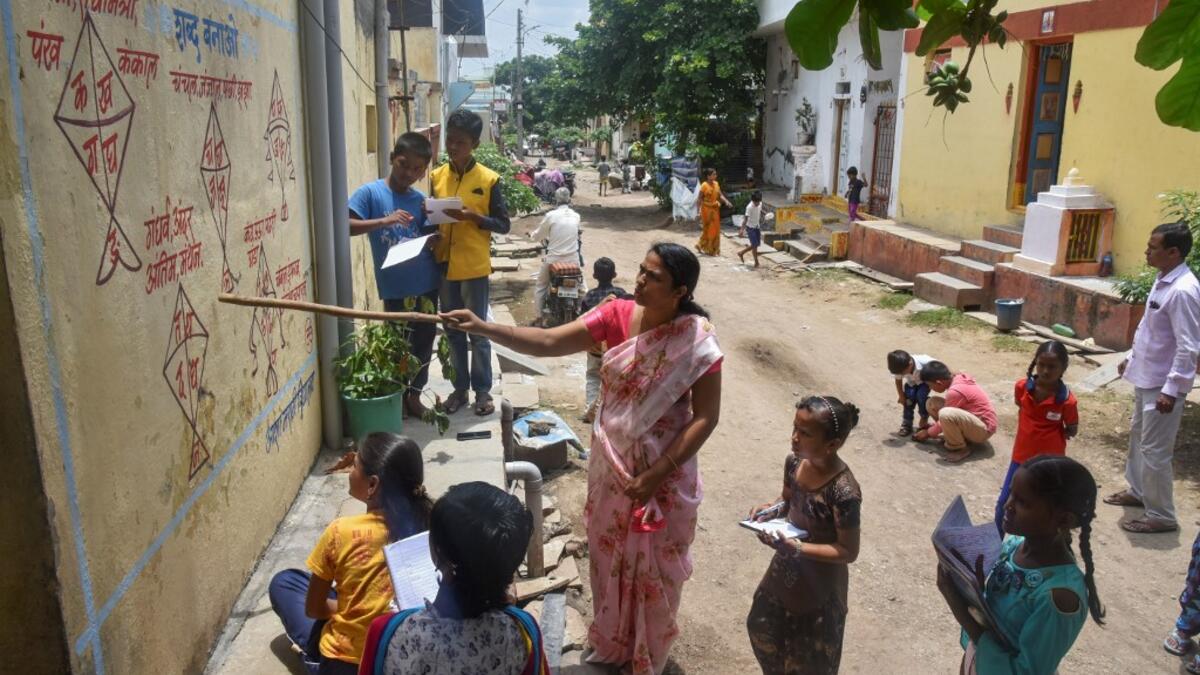 Half a dozen children in an Indian village gather around their teacher as she points a stick at a lesson painted on a wall, one of many which are part of an unusual effort to help poor students keep up with their education amid the coronavirus pandemic. AFP