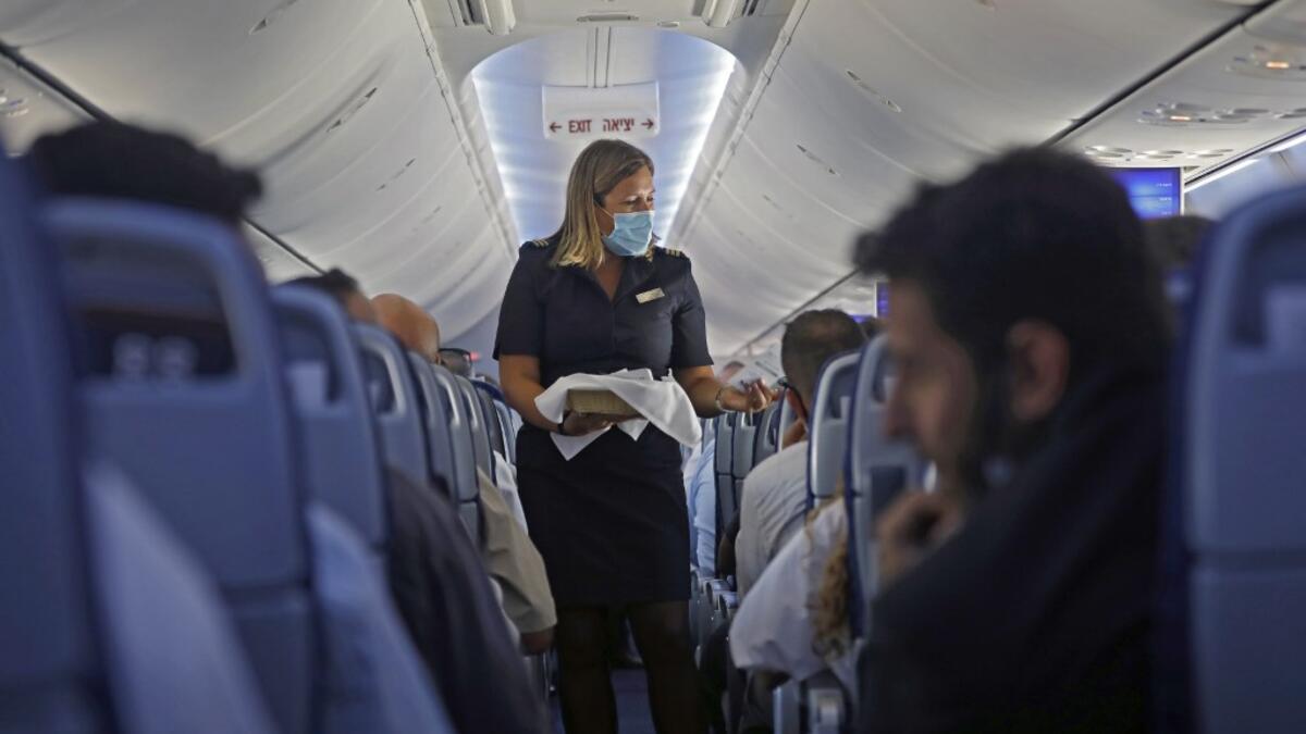 A flight attendant hands out chocolates with a greeting card to passengers on an El Al plane from Israel en route to Abu Dhabi, on August 31, 2020. A US-Israeli delegation including White House advisor Jared Kushner took off on a historic first direct commercial flight from Tel Aviv to Abu Dhabi to mark the normalisation of ties between the Jewish state and the UAE. NIR ELIAS / AFP
