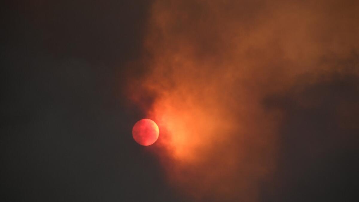 The sun is seen behind smoke from the Bobcat fire rising above in the Angeles National Forest above Duarte, California, about 27 miles (43 km) northeast of Los Angeles, September 7, 2020. Eight national forests in California have been closed as firefighters battle blazes across the state which is in the grips of a record-setting heat wave. Robyn Beck / AFP
