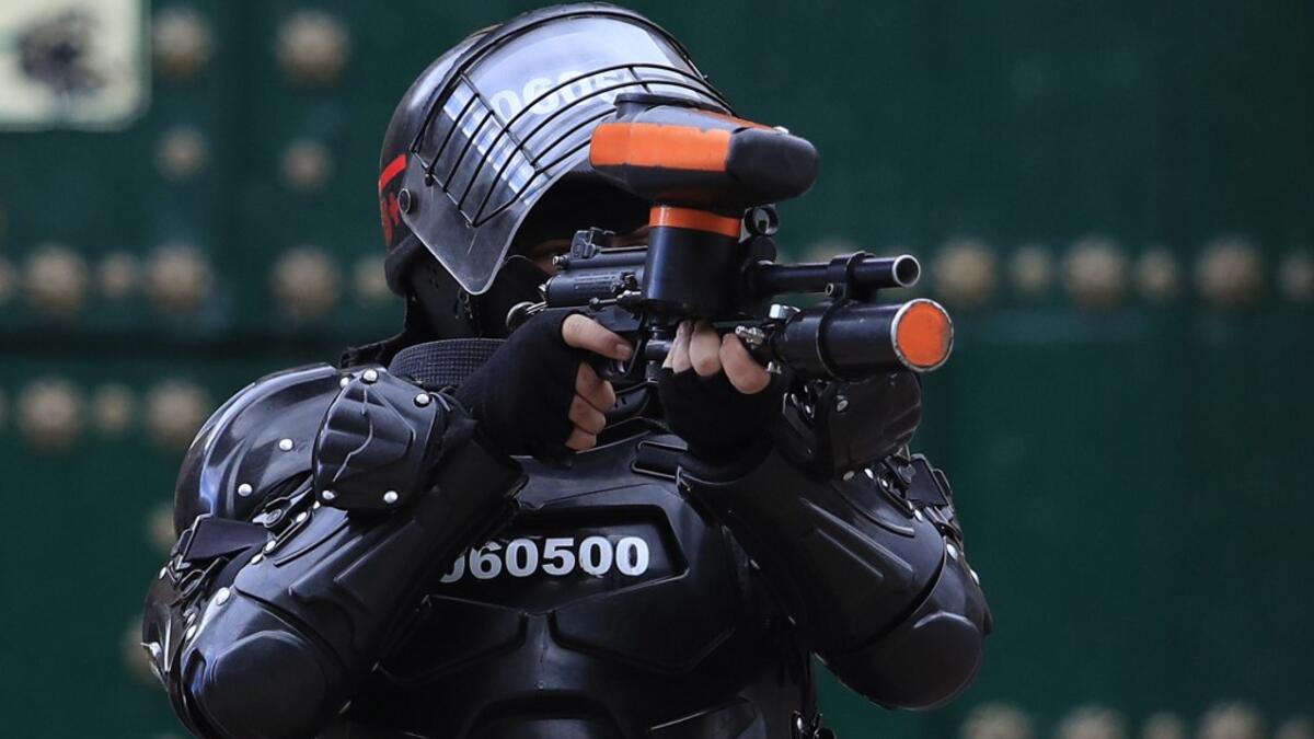 A riot police officer points his gun towards protestors during the fifth straight day of protests against police brutality in Bogota on September 13, 2020. Bogota's Mayor Claudia Lopez, apologized this Sunday for the abuses of the public force, in a ceremony that gathered relatives of the dead and wounded during the bloody protests that broke out five days ago against police brutality in Colombia. DANIEL MUNOZ / AFP