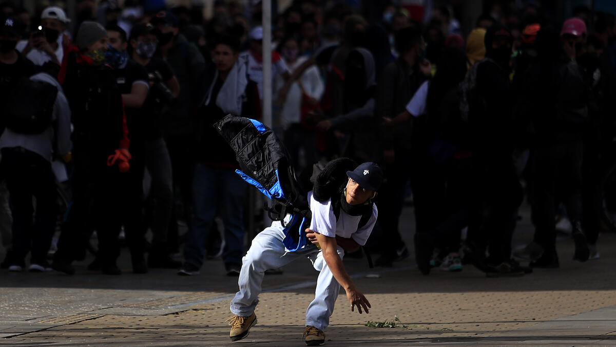 A protestor throws a stone towards riot police during the fifth straight day of protests against police brutality in Bogota on September 13, 2020. DANIEL MUNOZ / AFP