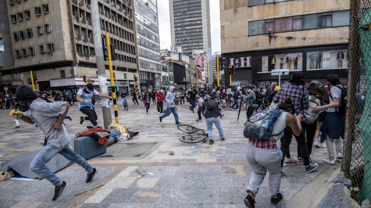 Demonstrators run for cover after clashes erupted during the fifth straight day of protests against police brutality in Bogota on September 13, 2020. Bogota's Mayor Claudia Lopez, apologized this Sunday for the abuses of the public force, in a ceremony that gathered relatives of the dead and wounded during the bloody protests that broke out five days ago against police brutality in Colombia. Juan BARRETO / AFP