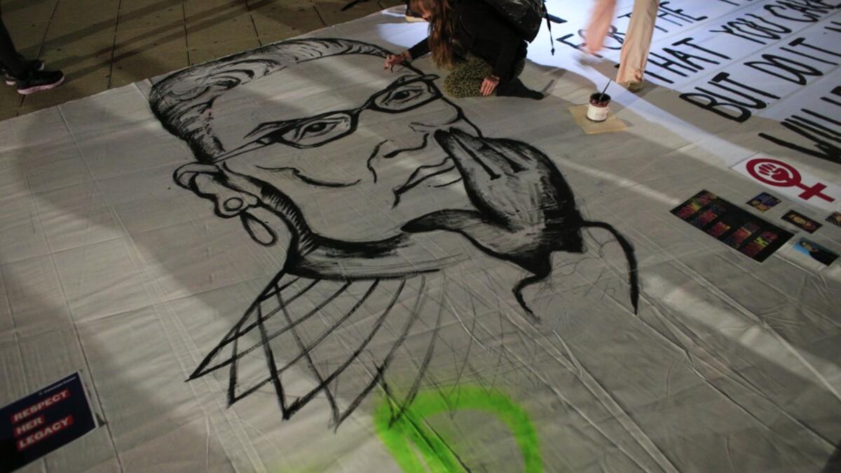 A woman paints an image of Ruth Bader Ginsburg as people pay their respects to her outside of the New York State Civil Supreme Court building in New York on September 19, 2020. US President Donald Trump vowed to quickly nominate a successor, likely a woman, to replace late Supreme Court Justice Ruth Bader Ginsburg, only a day after the death of the liberal stalwart. Kena Betancur / AFP