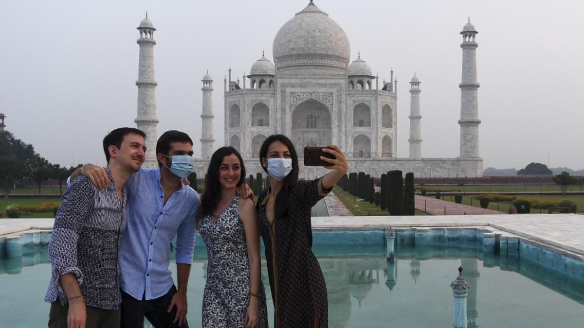 Tourists have their pictures taken at the Taj Mahal in Agra on September 21, 2020. The Taj Mahal reopened to visitors on September 21 in a symbolic business-as-usual gesture even as India looks set to overtake the US as the global leader in coronavirus infections. Sajjad HUSSAIN / AFP