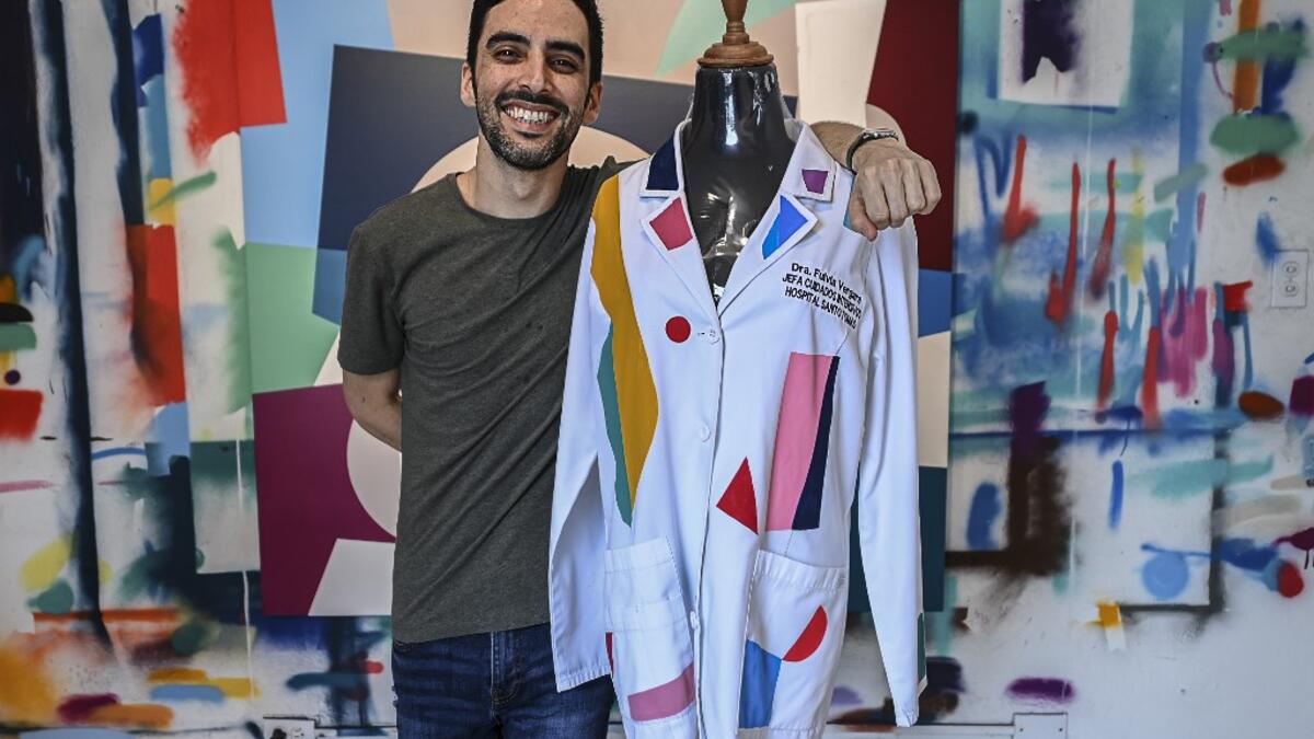 Panamanian artist Genaro Rodriguez poses with the white coat used by Dr. Fulvia Vergara and decorated by him in Panama City, on September 25, 2020. More than 20 doctor's coats fighting against COVID-19 that were disinfected and painted by Panamanian artists will be auctioned off from October 1 to 4. The funds will go to 20 health centers. Luis ACOSTA / AFP