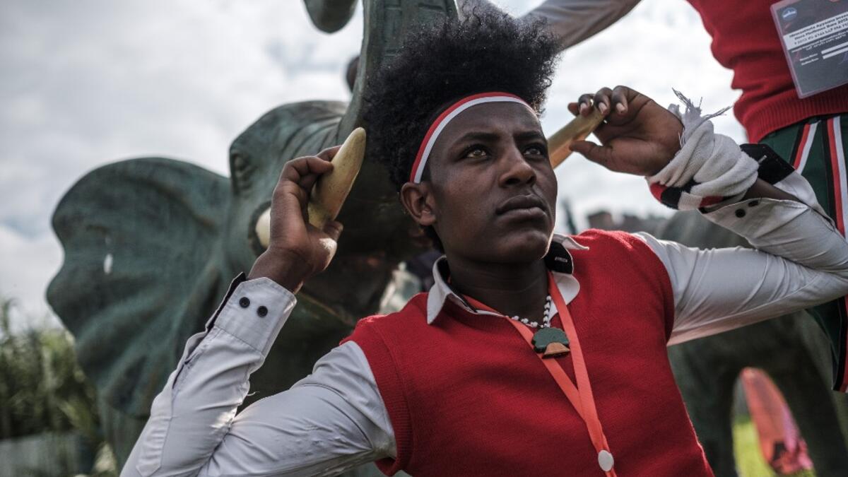 A young man in traditional clothing pose for a picture next to the statue of an elephant during the celebration of “Irreechaa”, the Oromo people thanksgiving holiday, in Addis Ababa, Ethiopia, on October 3, 2020. EDUARDO SOTERAS / AFP