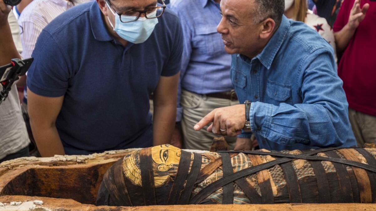 A picture taken on October 3, 2020 shows Egyptian Minister of Tourism and Antiquities Khaled Al-Anani (L), and Mustafa Waziri (R), Secretary General of the Supreme Council of Antiquities, unveil the mummy inside a sarcophagus excavated by the Egyptian archaeological mission working at the Saqqara necropolis, 30 kms south of the capital Cairo, which resulted in the discovery of a deep burial well with more than 59 human coffins closed for more than 2,500 years. They were unearthed south of Cairo in the spraw